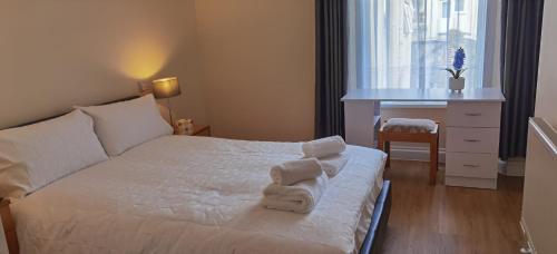 Un dormitorio con una cama blanca con toallas. en Entire 2 bedroom Apt in central location, Newly Refurbished, en Plymouth