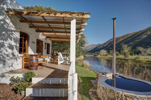 ein Haus mit einer Terrasse neben einem Fluss in der Unterkunft Somerset Gift Getaway Farm in Swellendam