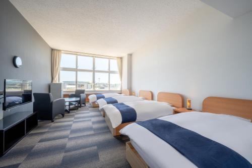 東松島市にあるKIBOTCHA/キボッチャのベッド4台、薄型テレビが備わるホテルルームです。