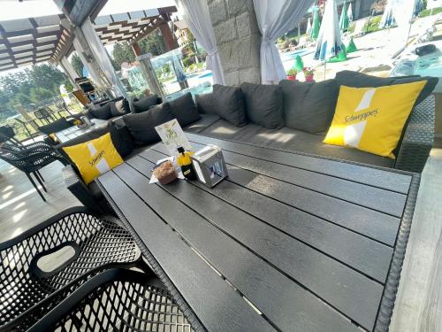 a wooden table with a couch and yellow pillows at Family Hotel Eterno in Tsigov Chark