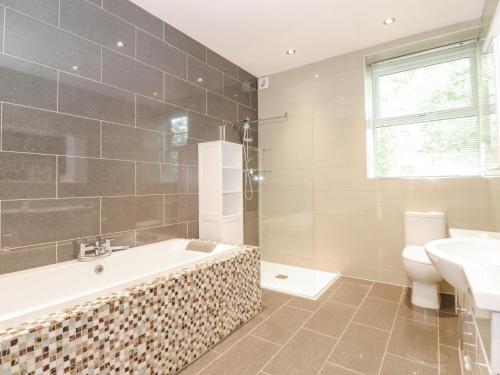 a bathroom with a tub and a toilet and a sink at The Gatehouse in Kendal