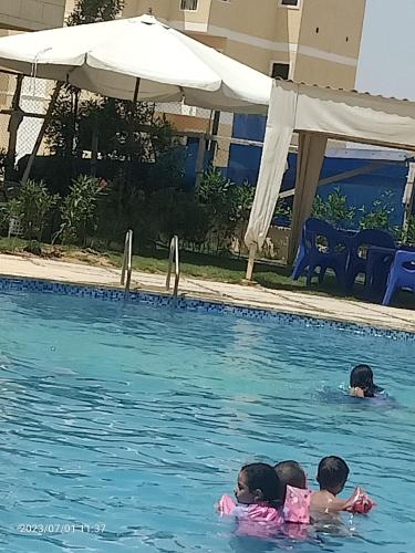 Tres niños están nadando en una piscina en استديو مكيف ب ٦٥٠ اليوم ك ٨٤ قبلي أمام زهران والزهور, en Abû Zeira