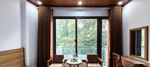 a room with a table and chairs and a large window at Rosalia Tam Đảo Hotel in Tam Ðảo
