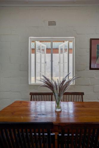 a dining room table with a vase on it with a window at Somerset Gift Getaway Farm in Swellendam