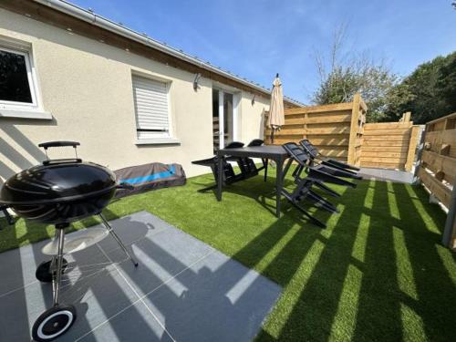 a grill and picnic table in a backyard at La chaumière in Longues-sur-Mer