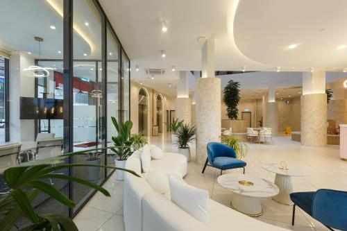 a lobby with white furniture and blue chairs at Wellesley Hotel in Simpang Ampat