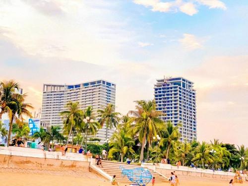 una spiaggia con due edifici alti e palme di FLC Sea Tower Quy Nhon -Tran Apartment a Quy Nhon