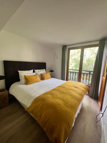 - une chambre avec un grand lit et une couverture jaune dans l'établissement N5 Megève - Résidence de L'ours - appart 4 pers, à Megève