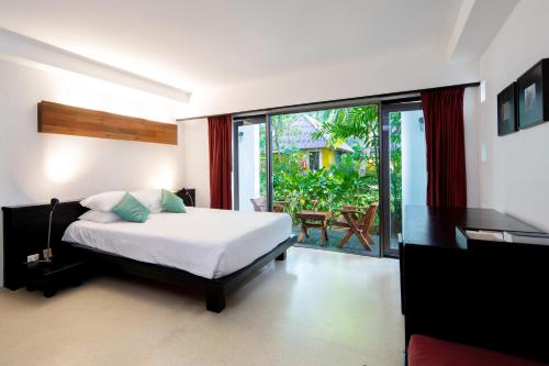 a bedroom with a bed and a view of a patio at Haadson Resort - Khaolak, Phangnga in Khao Lak