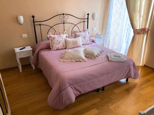 una camera da letto con un grande letto con lenzuola e cuscini rosa di B&B in Piazzetta a Sarzana