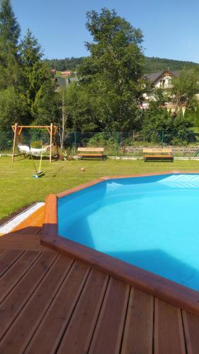 a blue swimming pool on a deck with a playground at Czesławka in Zawoja