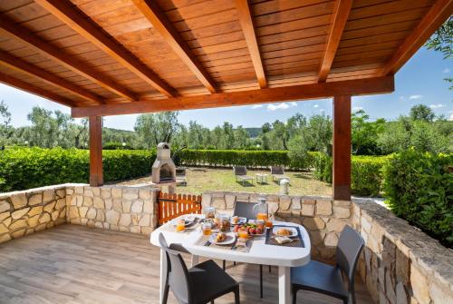 a patio with a white table and chairs under a wooden pergola at Agriturismo I Tesori del Sud Vieste, Puglia in Vieste