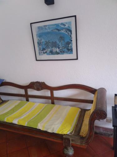 Cama de madera en una habitación con una foto en la pared en Olivia Bungalow, en Wattala