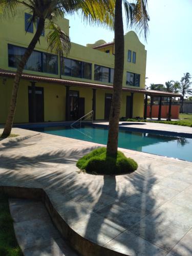 a building with a swimming pool and two palm trees at Olivia Bungalow in Wattala