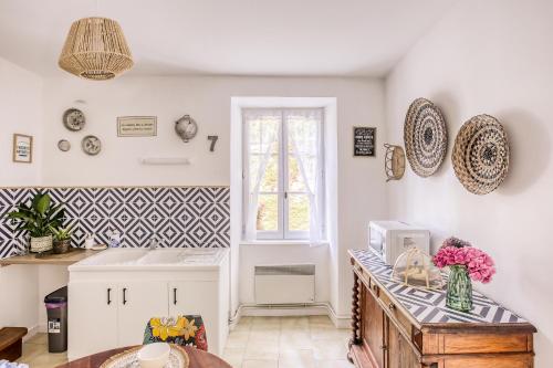 una cocina con paredes blancas y un mostrador con flores. en Gîte L'Escale - Maison de charme, en Chambellay