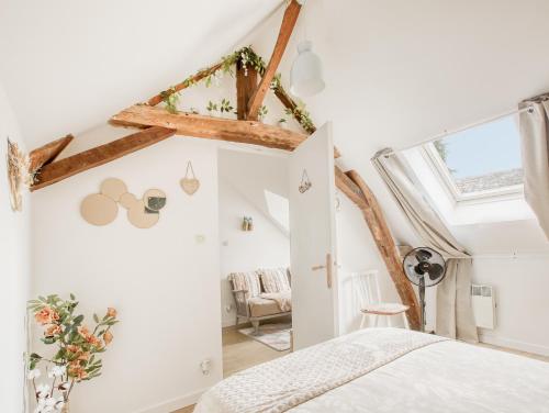 1 dormitorio con paredes blancas y techo con vigas. en Gîte L'Escale - Maison de charme, en Chambellay