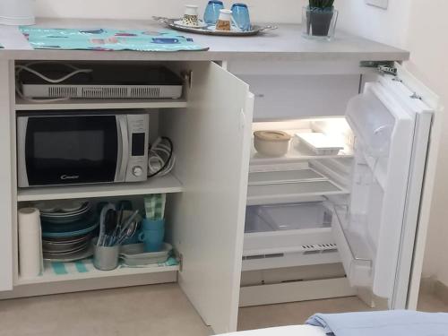 a white refrigerator with a microwave inside of it at Monolocale Versilia in Lido di Camaiore