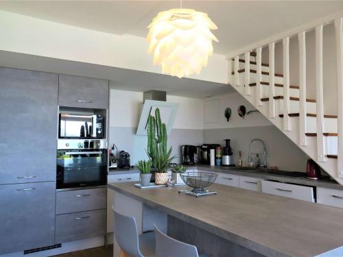 une cuisine avec un grand îlot doté de placards blancs et d'un lustre dans l'établissement Maison à 250m de la plage avec terrasse et vue mer à Perros-Guirec - FR-1-368-191, à Perros-Guirec