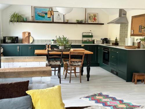 una cucina con armadi verdi e tavolo in legno di The Wimberry a Blackwater