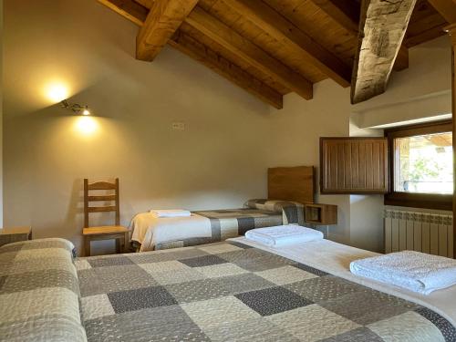 a bedroom with two beds and a wooden ceiling at Palacio de Aralar Alta Familias in Oskotz