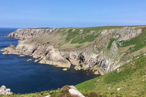 a large cliff next to the ocean with green grass at Studio at Church House in Bideford