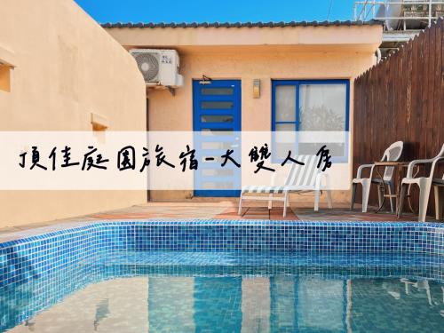 a villa with a swimming pool in front of a house at Ding Jia Garden Resort in Hengchun