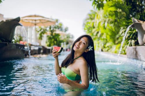 a woman in a swimming pool holding a drink at The Ritz-Carlton, Bangalore in Bengaluru