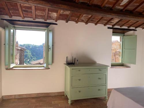 a bedroom with a green dresser and two windows at Civita Secret Lodge in Lubriano