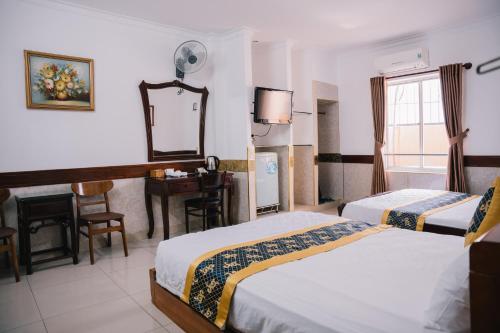 a hotel room with two beds and a desk and a mirror at HUNG HUONG HOTEL in Ho Chi Minh City