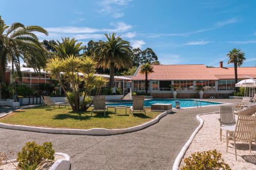 un complejo con piscina, sillas y palmeras en Makkan Club, en Oleiros