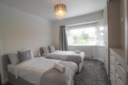 a bedroom with two beds and a chandelier at Upton Hidden Garden Retreat in Birkenhead