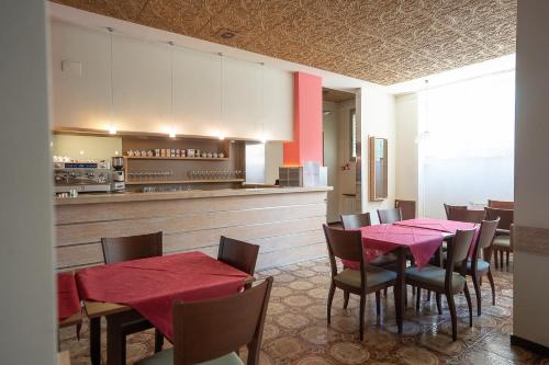 a restaurant with red tables and chairs and a kitchen at Hotel Napoleon in Pontremoli