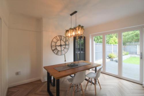 a dining room with a table and chairs and a chandelier at Upton Hidden Garden Retreat in Birkenhead