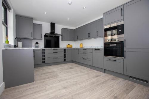 una cocina con armarios grises y electrodomésticos de acero inoxidable en Stylish Stay Near The Stadium Walk To The Action, en Liverpool
