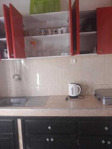 um balcão de cozinha com um lavatório e armários vermelhos em منزل الضيافة em Rabat