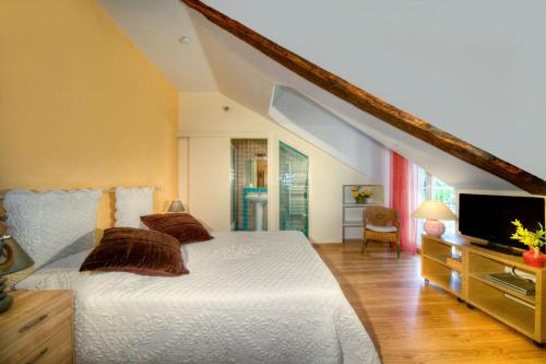 1 dormitorio con 1 cama blanca y TV en Chambres d’hôtes les Cardabelles en Saint-Jean-du-Bruel