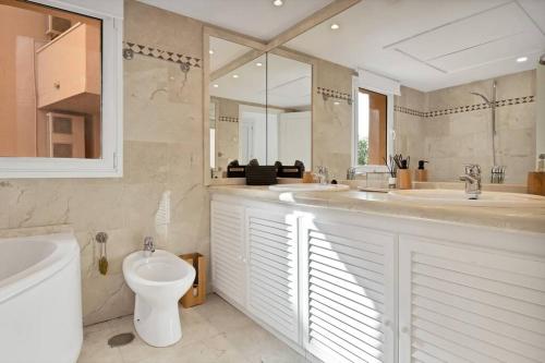 a bathroom with two sinks and a toilet and a mirror at Ubicación y vistas panorámicas en Nueva Andalucía - MAGNA MARBELLA 108 in Marbella