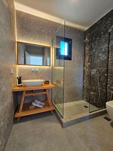 a bathroom with a sink and a glass shower at Byblos Cycladic House in Vívlos