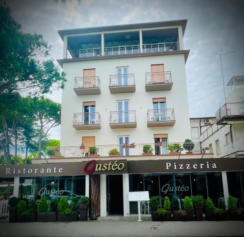a tall white building with balconies on it at Hotel Cristina in Lido di Jesolo