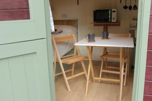 a small kitchen with a table and a microwave at Cosy Shepherd's Hut with Hot Tub in Church Stretton