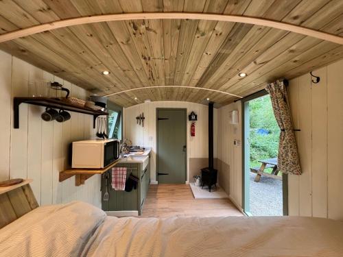 a room with a bed and a kitchen in a tiny house at Cosy Shepherd's Hut with Hot Tub in Church Stretton