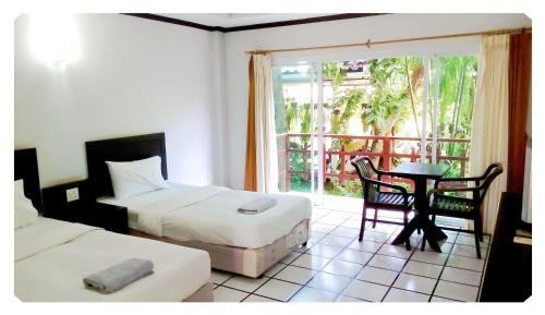 a bedroom with two beds and a table and a window at Thong Paeka Hotel in Prasat