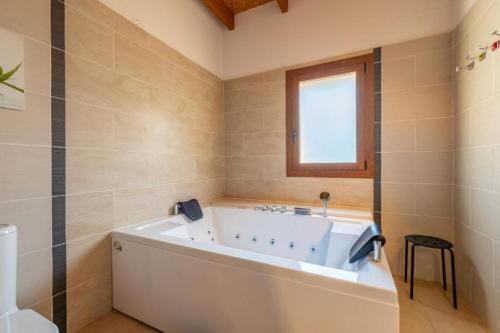 a white tub in a bathroom with a window at Villa Es Figueral in Campos