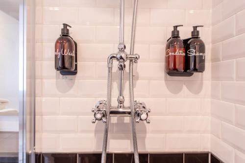 um chuveiro com quatro garrafas de sabão na casa de banho em Gunmakers em Londres