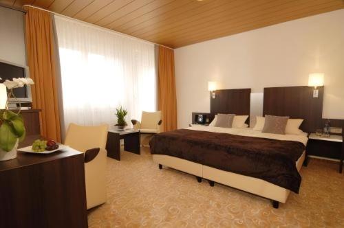 Habitación de hotel con cama grande y escritorio. en Adler Hotel Garni en Ostfildern