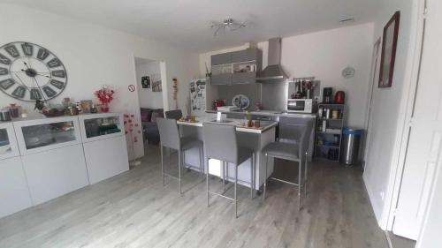 cocina con mesa, sillas y reloj en Chez Laura, en Moigny