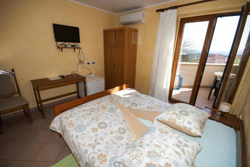 a bedroom with a bed and a balcony with a television at Guesthouse Villa Lena in Premantura