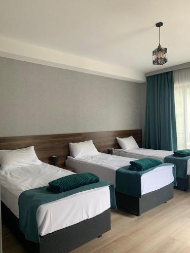 three beds in a room with blue curtains at Hotel GENI Kazbegi in Stepantsminda
