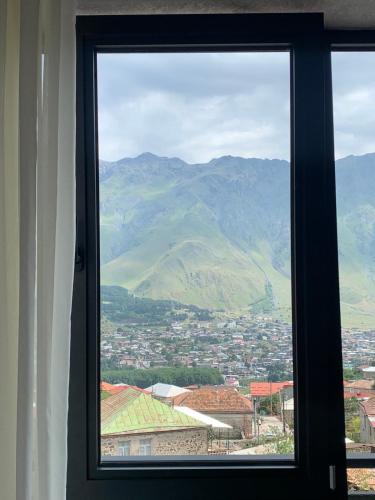 a window with a view of a city and mountains at Hotel GENI Kazbegi in Stepantsminda