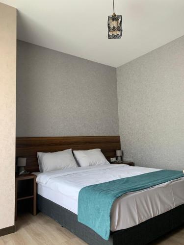 a bedroom with a large bed with a blue blanket at Hotel GENI Kazbegi in Stepantsminda